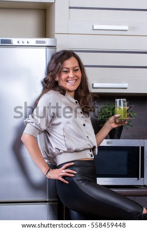 Young woman with drinking vegetable juice in kitchen