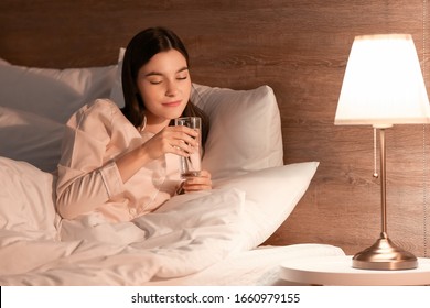 Young Woman Drinking Water In Bedroom At Night