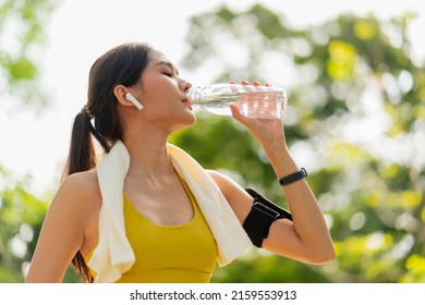 young Woman drinking water from bottle. asian female drinking water after exercises or sport. Beautiful fitness athlete woman wearing hat drinking water after work out exercising on sunset evening - Shutterstock ID 2159553913
