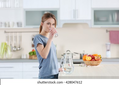Young Woman Drinking Water From Glass In The Kitchen