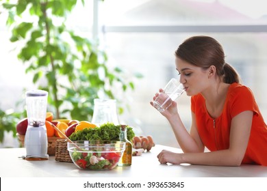 Young Woman Drinking Water Near Table With Fruits And Vegetables In The Kitchen