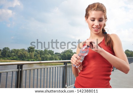 Young woman drinking water at outdoors workout