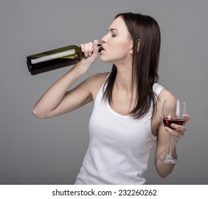 Young Woman Is Drinking Wine From Bottle.