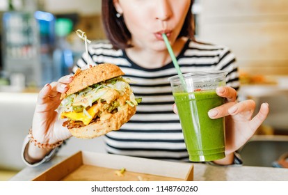 A Young Woman Drinks Green Smoothies And Eats A Burger In A Vegan Fast Food Restaurant