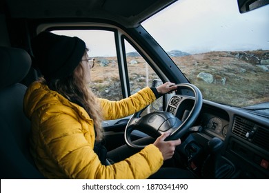 Young Woman Drive Camping Van On Epic Mountain Road. Female Adventurer Travel In Remote Locations To Camping Destination. Vanlife Lifestyle For Urban Travellers 