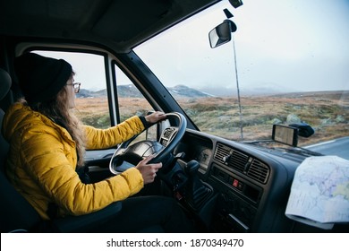 Young Woman Drive Camping Van On Epic Mountain Road. Female Adventurer Travel In Remote Locations To Camping Destination. Vanlife Lifestyle For Urban Travellers 