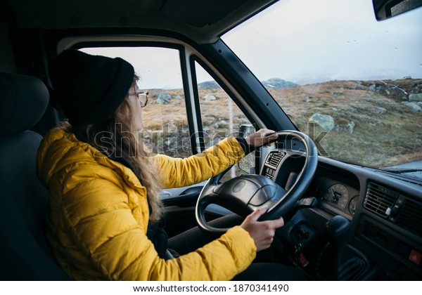 Young woman drive camping\
van on epic mountain road. Female adventurer travel in remote\
locations to camping destination. Vanlife lifestyle for urban\
travellers 