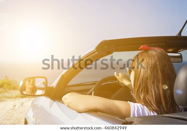 Young woman drive a car\
on the beach.