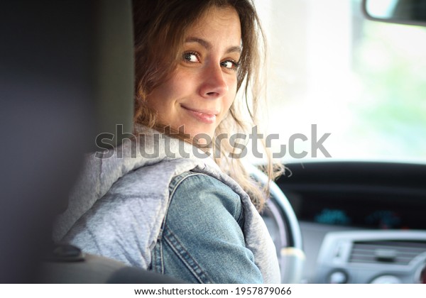 Young woman driver beginner. Girl look
back in the vehicle interior. Female car
driver.