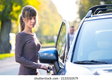 Young woman driver enjoying warm summer day standing beside her car on city street. Travelling and vacation concept. - Shutterstock ID 2133310579