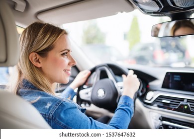 Young woman driver sitting in car, driving.