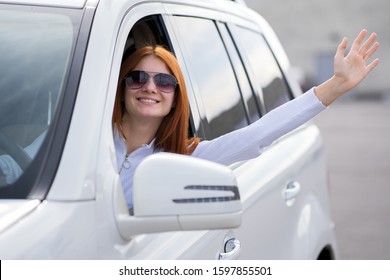 Young Woman Driver Waving Her Hand Behind Car Steering Wheel.