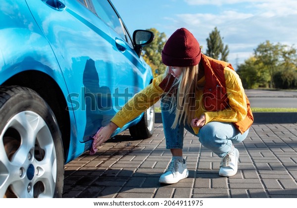 a young woman, a driver, wiping a car with a\
microfiber cloth after washing, washing a car. Self-service\
transport, care concept. Car\
wash