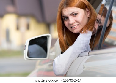 Young Woman Driving A Car Backwards. Girl With Funny Expression On Her Face While She Made A Fender Bender Damage To A Rear Vehicle.