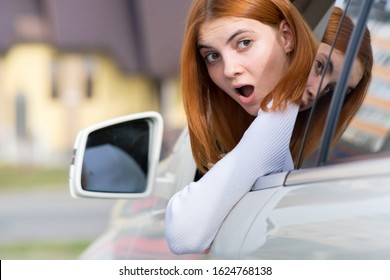 Young Woman Driving A Car Backwards. Girl With Funny Expression On Her Face While She Made A Fender Bender Damage To A Rear Vehicle.