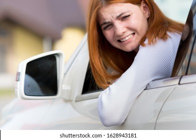 Young Woman Driving A Car Backwards. Girl With Funny Expression On Her Face While She Made A Fender Bender Damage To A Rear Vehicle.