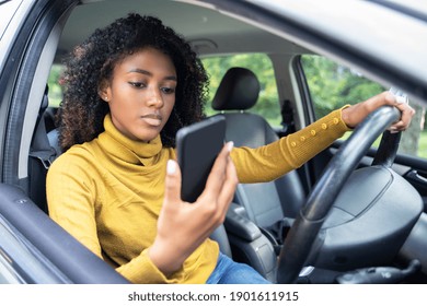 Young Woman Driving Car And Checking Her Phone.