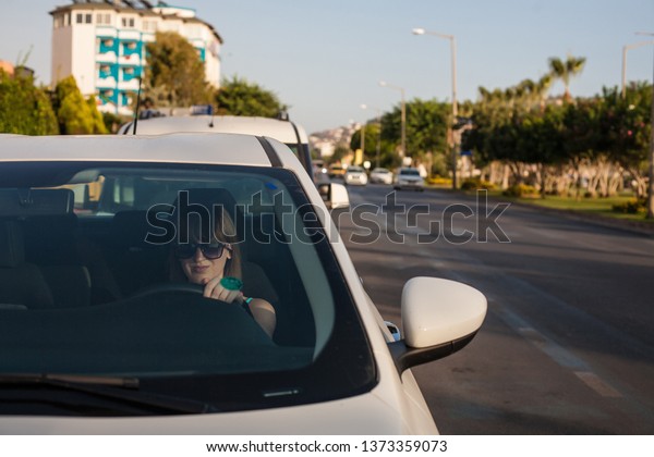 Young woman driving a car in the\
city. Portrait of a beautiful woman in a car. Travel and vacations\
concepts. Happy woman inside a car driving in the street.\
