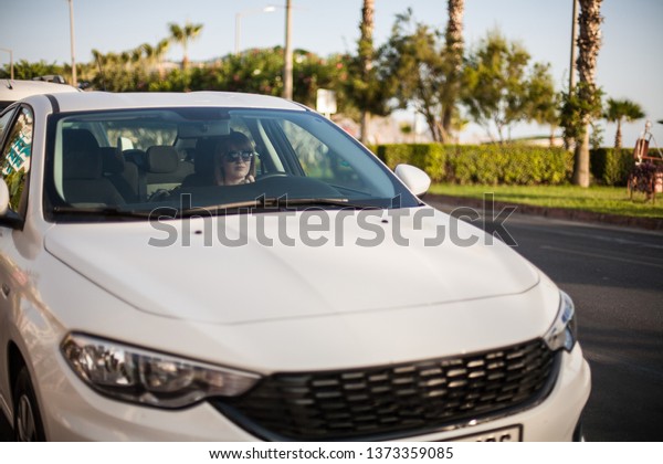 Young woman driving a car in the\
city. Portrait of a beautiful woman in a car. Travel and vacations\
concepts. Happy woman inside a car driving in the street.\
