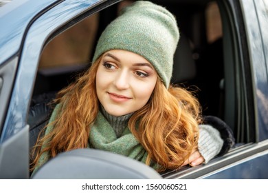 Young Woman Driving A Car. Green Hat And Scarf. Concept Lifestyle, Autumn, Winter, Auto Driver.