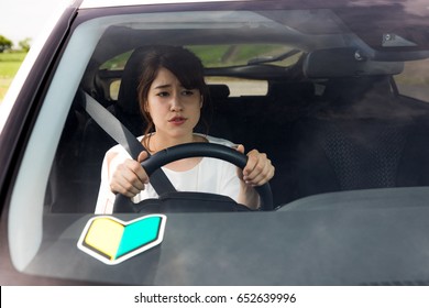 young woman driving a car with japanese sticker for new car drivers.