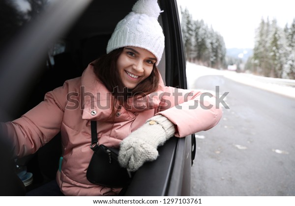 Young woman driving car and looking out of\
window on road. Winter\
vacation