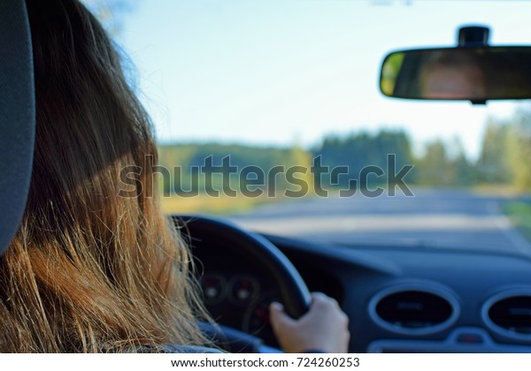 Young\
woman driving a car. Rear view horizontal\
image.