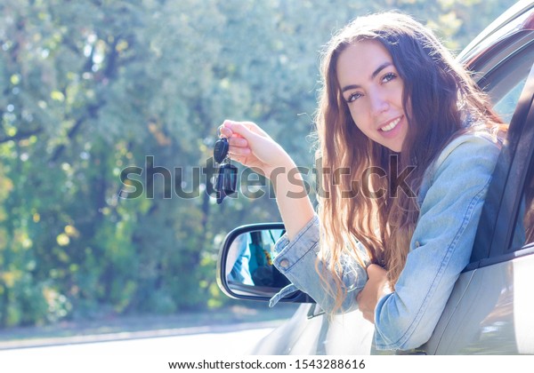 Young\
woman driving her car. Attractive young girl driver in new car .\
girl bought a car. shows the keys to a new\
car