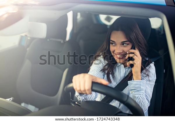 Young woman\
driving his car and talking on the phone. Woman Talking on Mobile\
while Driving. Businesswoman multitasking while driving, drinking\
coffee and talking on the\
phone