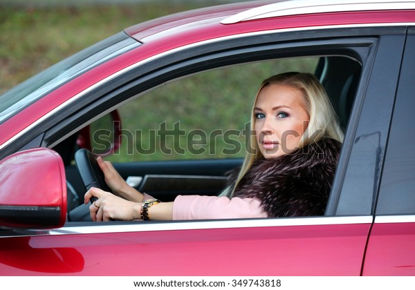 young woman driving red\
car