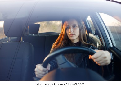 Young woman driving rented or new car in the evening. Automobile rent image background