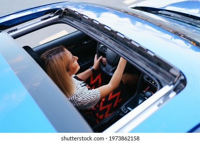 Young Woman Driving With Sunroof Open