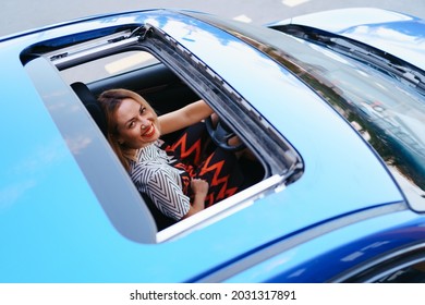 Young Woman Driving With Sunroof Open