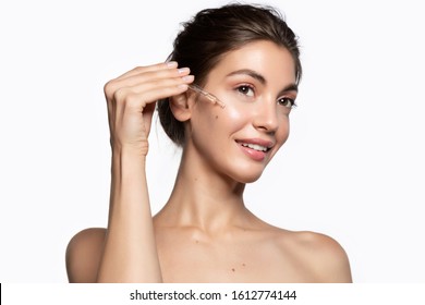 Young Woman Dropping Oil With Pipette On Face For Fresh Perfect Skin. 