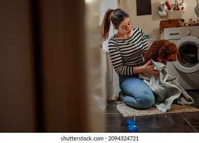 Young Woman Drying Her Adorable Dog With Towel On The Floor In The Bathroom After His Bath