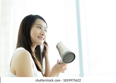 Young Woman Drying Her Hair With A Hair Dryer