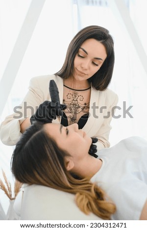 Young woman during procedure of permanent eyebrow makeup.