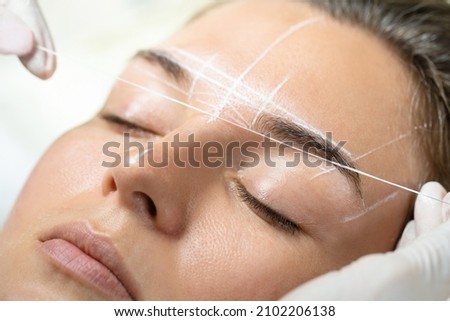 Young woman during professional eyebrow mapping procedure before permanent makeup