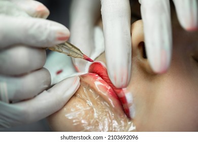 Young woman during professional permanent makeup procedure - lip blushing