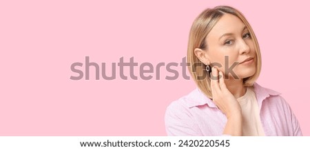 Young woman with ear piercing on pink background with space for text