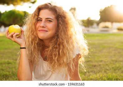 Young Woman Eating An Apple At Park