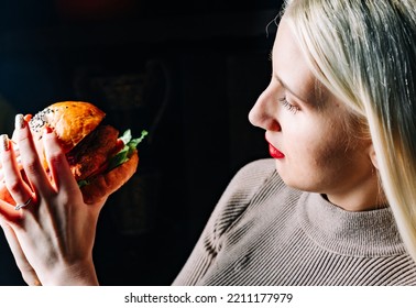 Young Woman Eating Burger On Black Background