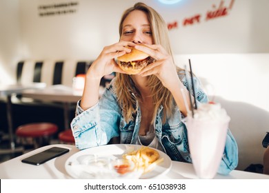 Young Woman Eating Burger In Restaurant 