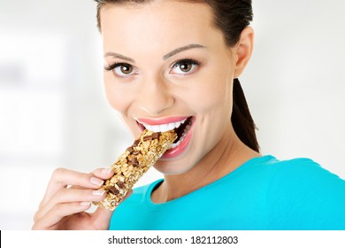 Young woman eating Cereal candy bar, isolated on white