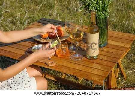 Young woman eating cheese with honey on romantic picnic outdoors