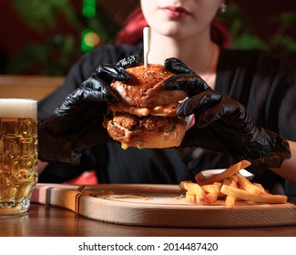 Young Woman Eating Chicken Burger With A Pint Of Beer Nearby