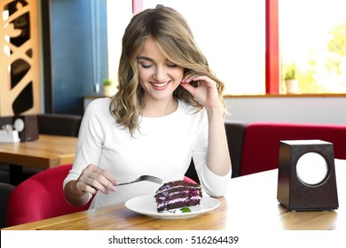 Young Woman Eating Delicious Dessert At Restaurant