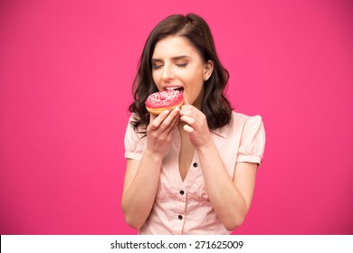 Young Woman Eating Donut Over Pink Background