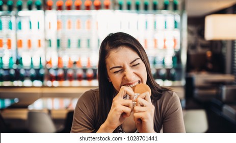 Young Woman Eating Fatty Hamburger.Craving Fast Food.Enjoying Guilty Pleasure,eating Junk Food.Satisfied Expression.Breaking Diet Rules,giving Up Diet.Unhealthy Imbalanced Nutrition Calorie Intake.