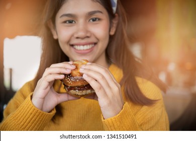 Young Woman Eating Fatty Hamburger.Craving Fast Food.Enjoying Guilty Pleasure, Eating Junk Food.Satisfied Expression.Breaking Diet Rules ,giving Up Diet.Unhealthy Imbalanced Nutrition Calorie Intake.